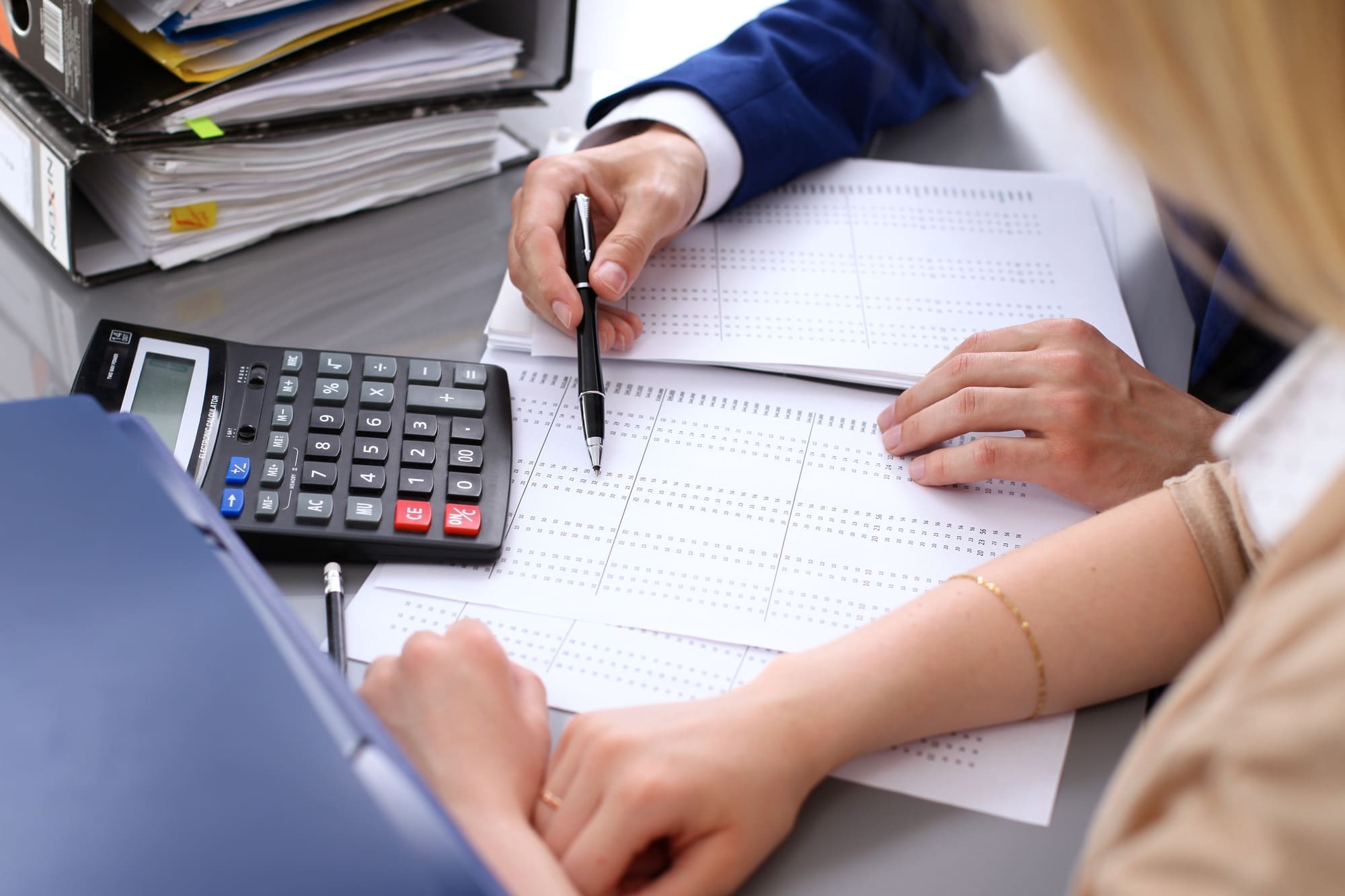 Bookkeeper or financial inspector and secretary making report, calculating or checking balance.