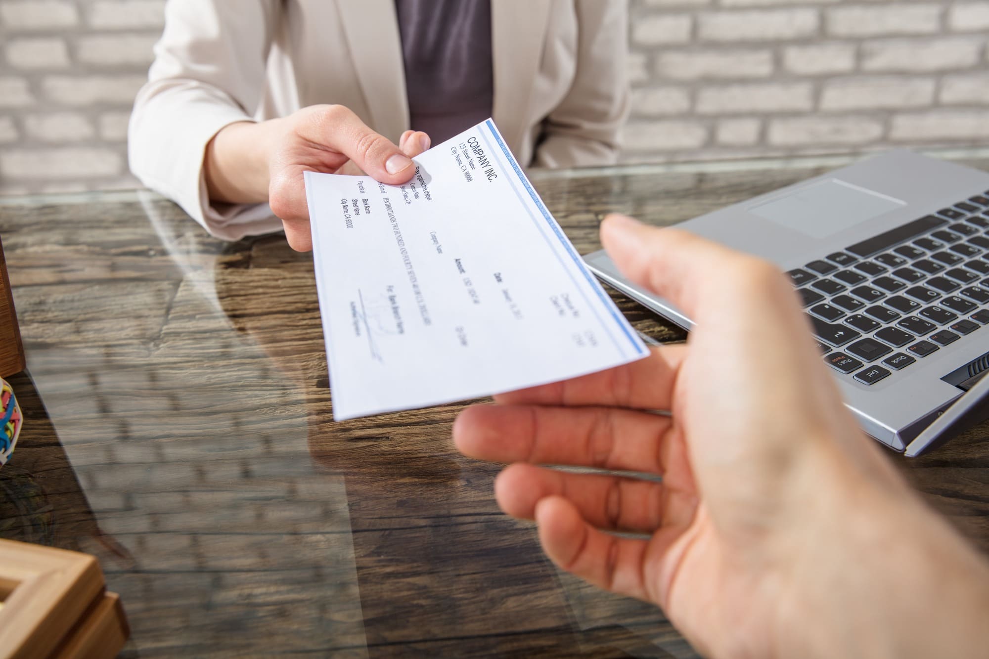 A person gives a check to another person at a desk